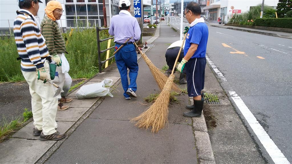 歩道をほうきで掃いている写真