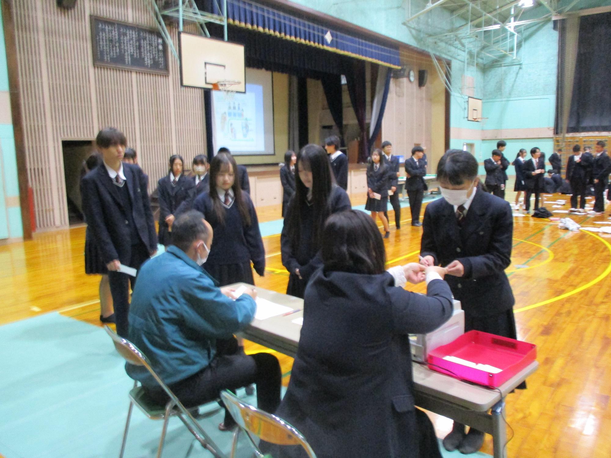 選挙人名簿照合後、投票用紙を受けておる生徒